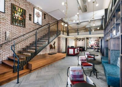 Modern interior with exposed brick walls, a wooden staircase, contemporary lighting, seating area with tables and chairs, and art on the walls.