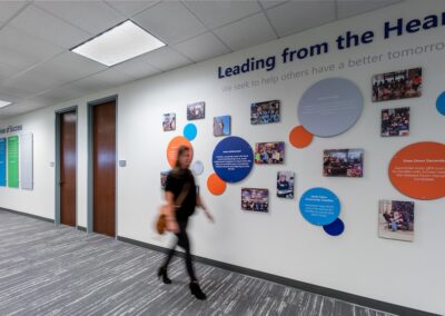 A person walks down a hallway with colorful wall displays featuring text and photos, and the phrase "Leading from the Heart" prominently displayed above.