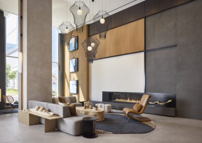 Modern lobby with large sectional sofa, lounge chair, built-in fireplace, contemporary lighting fixtures, and tall windows letting in natural light.